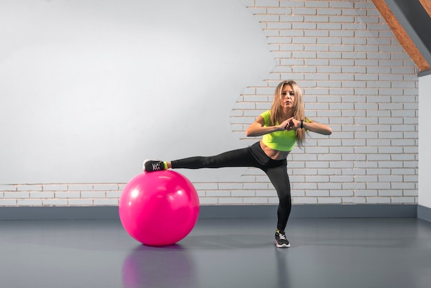 Vrouw op de sportschool met pilatesbal Meisjesatleet squats met fitnessbal Sport en gezond levensstijlconcept