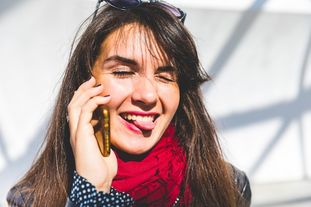 Vrouw op de telefoon die tong toont aan de camera