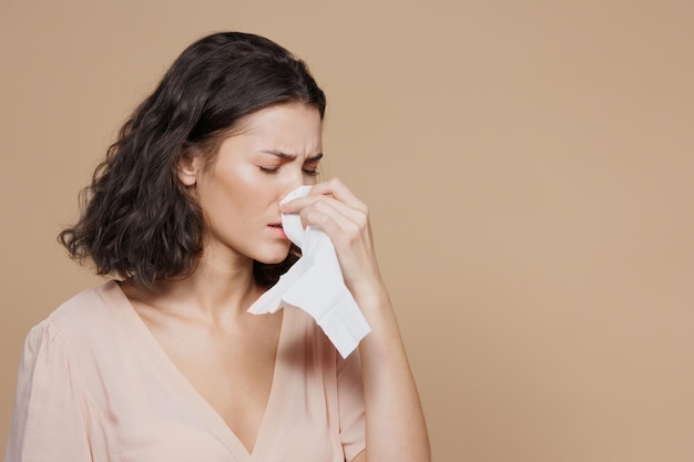 Vrouw op een beige achtergrond niest en veegt haar neus af met een witte servet reclameposter van a