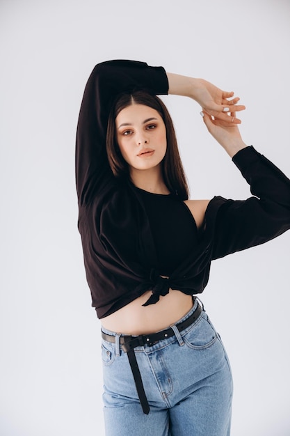 vrouw op een cyclorama in een studio, gekleed in een jeans met hoge taille en een kort t-shirt met een blote buik