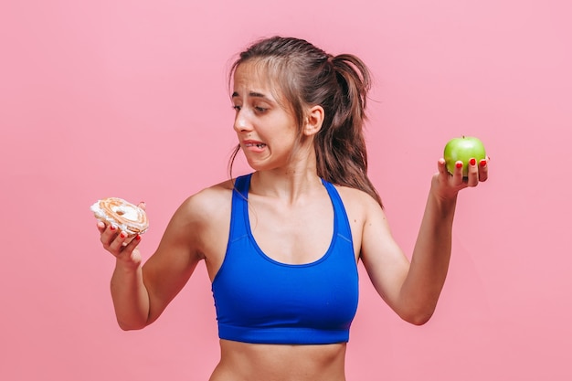 vrouw op een roze muur met een cake en een appel