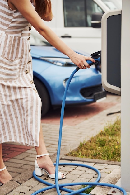 Vrouw op het laadstation van elektrische auto's overdag Brand nieuw voertuig