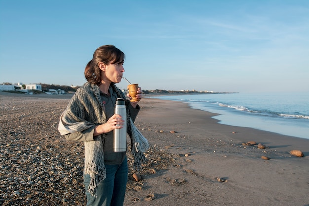 Vrouw op het strand drinkt mate