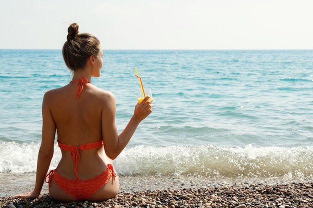 Vrouw op het strand met een glas cocktail