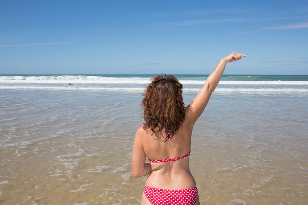 Vrouw op het strand wijst met haar vinger