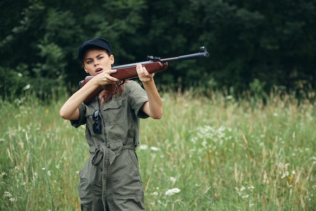 Vrouw op jacht met een pistool in groene overalls groene bladeren bos achtergrond