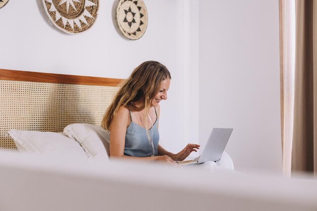 Vrouw op kantoor die op het bed zit en naar haar laptop kijkt