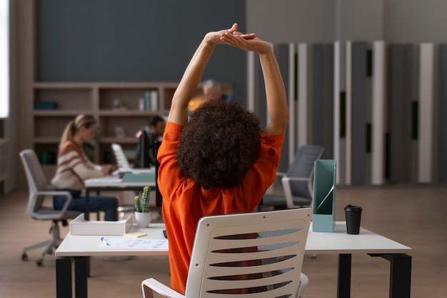 Foto vrouw op kantoor die zich uitstrekt tijdens een werkdag