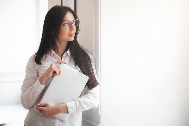 Vrouw op kantoor vrouw houdt laptop binnenshuis vast businesslady