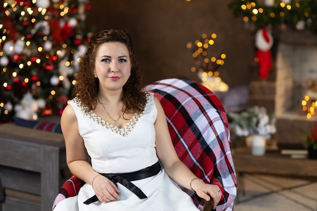 Vrouw op kerstavond in fauteuil thuis in nieuwjaarsinterieur