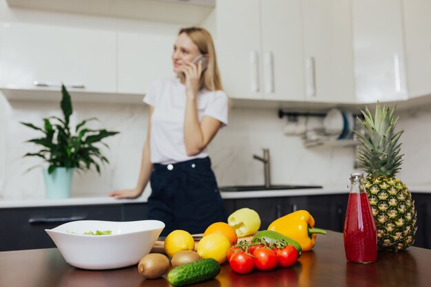 vrouw op keuken praten over de telefoon tijdens het koken van de lunch