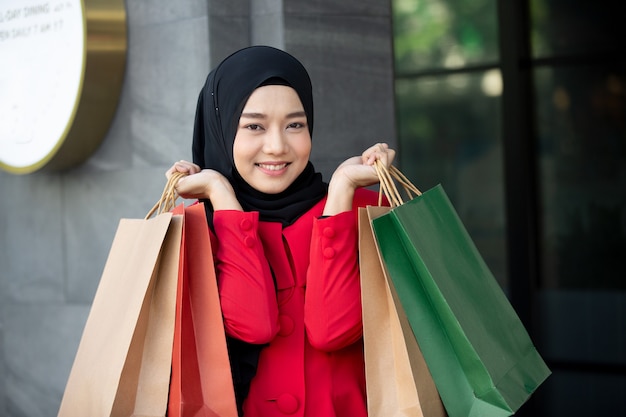 vrouw op rode kleding met boodschappentassen die buiten staan