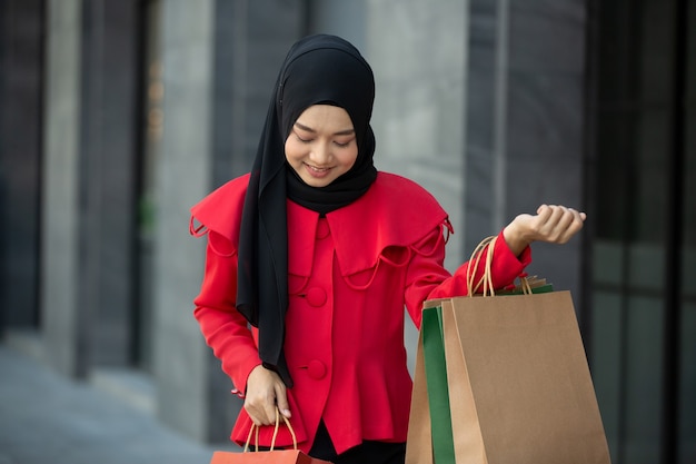 vrouw op rode kleding met boodschappentassen die buiten staan