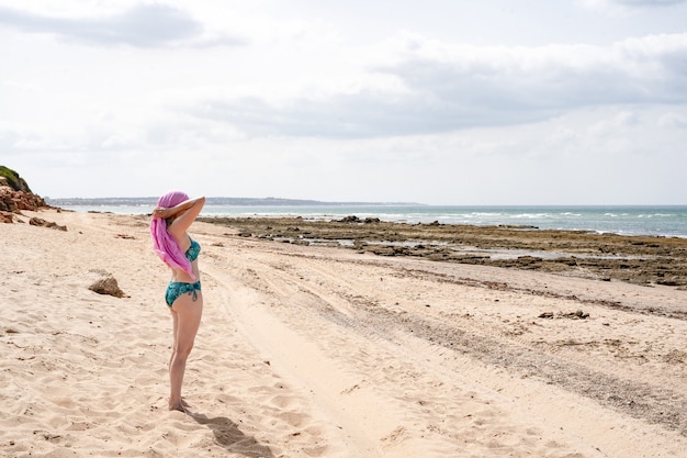 Vrouw op strand bindt roze hoofddoek, kanker