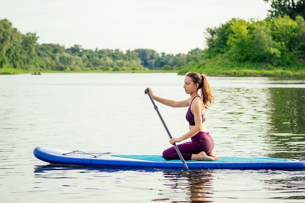 Vrouw op sup sup board in de natuur 's avonds