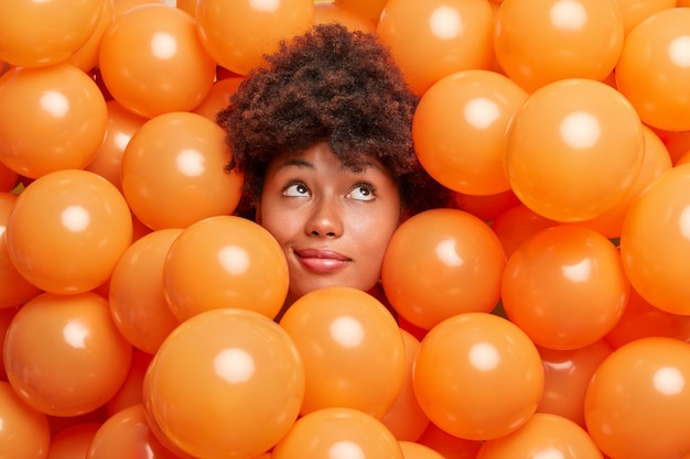 vrouw op verjaardagsfeestje omringd met kleine oranje ballonnen