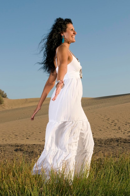 vrouw op zand genietend van lente- of zomerzon gekleed in witte kleren