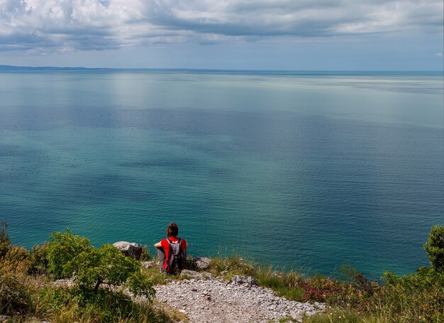 Vrouw op zoek naar de adriatische zee vanaf de rand van de karst nabij triëst, italië