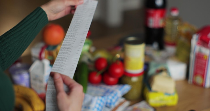Foto vrouw op zoek naar een cheque van een supermarkt kruidenier en supermarkt koken en eten product op de achtergrond