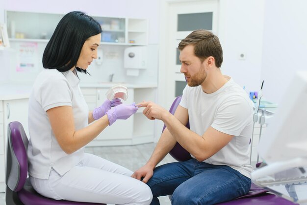 Vrouw orthodontist Tandarts toont menselijke kaak Prothese van tanden en tandvlees Vrouw arts demonstreert visueel hulpmiddel voor studenten Concept van opleiding orthodontisten Zorg voor uw tandheelkundige gezondheid