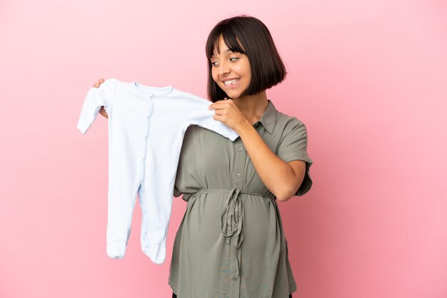 Vrouw over geïsoleerde achtergrond zwanger en met babykleertjes