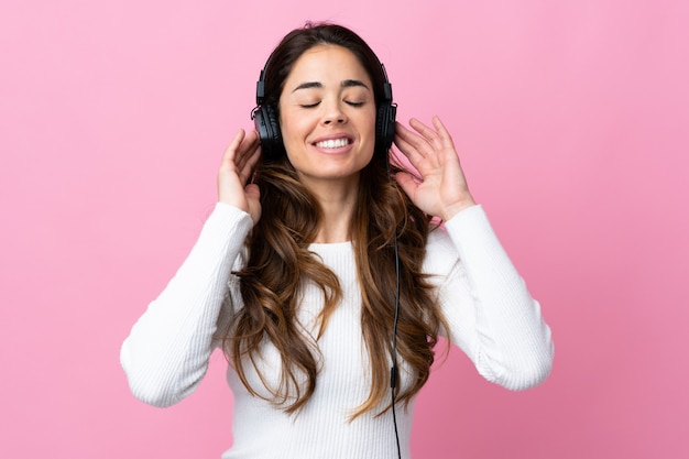 Vrouw over geïsoleerde roze het luisteren muziek en het zingen