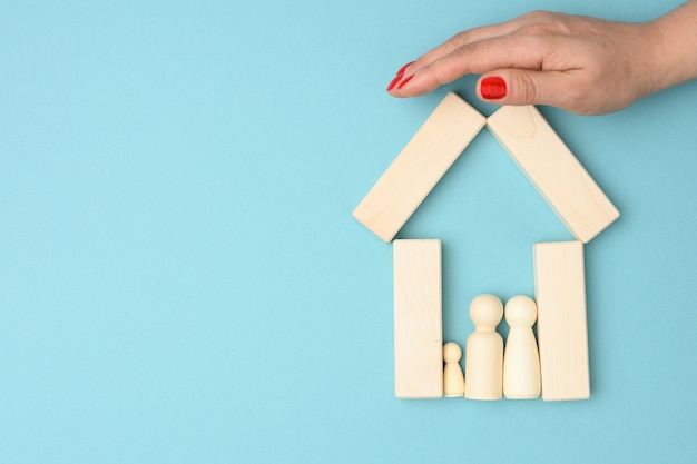 Vrouw overhandigt miniatuur houten huis met familie
