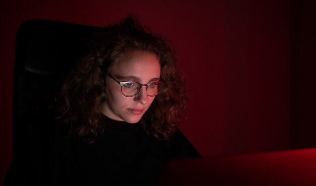 Foto vrouw overweldigd tijdens het werken op de computer 's nachts met rood licht