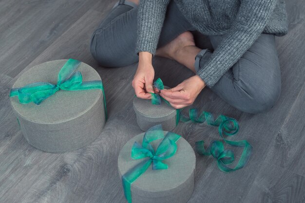 vrouw pack geschenken met grijze ronde dozen en groen lint