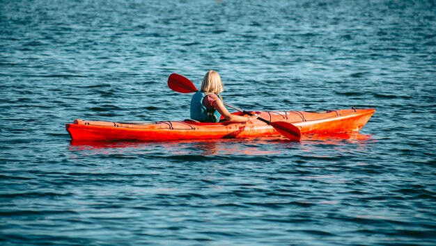 Vrouw peddelen een rode kajak in de rivier overdag