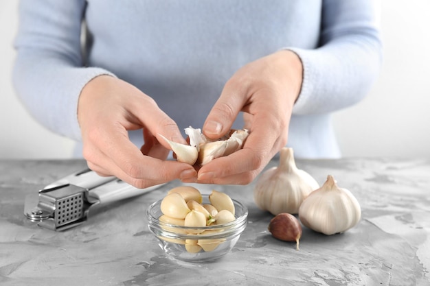 Vrouw pelt knoflook aan tafel