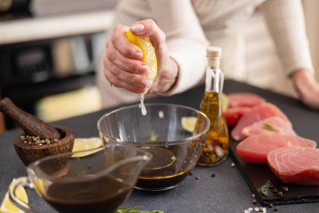 Foto vrouw persen vers citroensap in glazen schaal met sojasaus en olijfolie maken marinade om