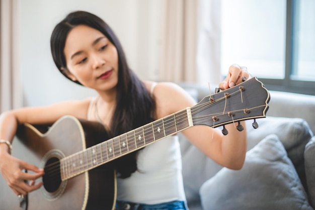 Vrouw persoon spelen akoestische gitaar muziekinstrument thuis jonge Aziatische muzikant meisje levensstijl