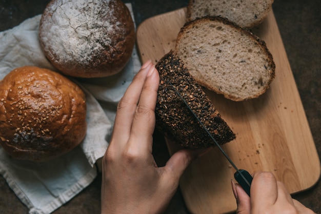 Vrouw plakjes broodje op houten bord