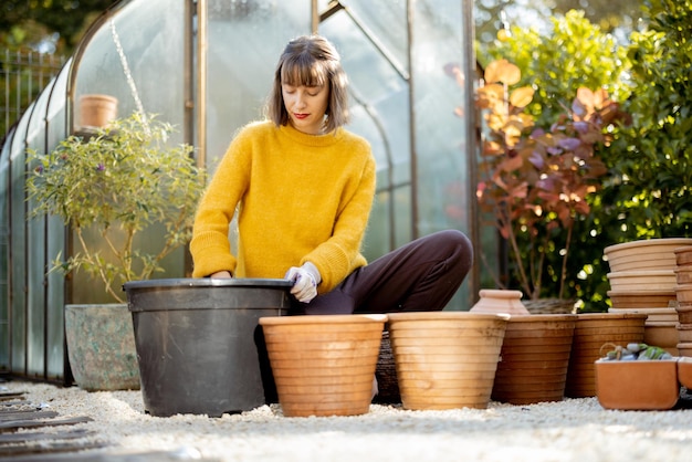 Vrouw plant bloemen in kruiken in de tuin