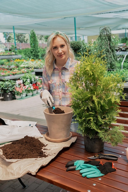 Vrouw plant een struik in bloempot met vuil in tuincentrum