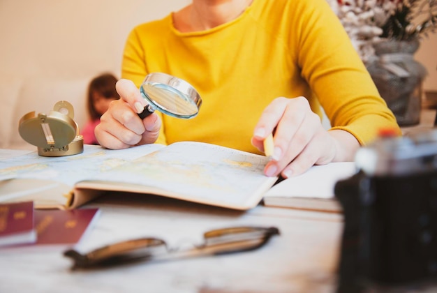 Vrouw plant tour met reiskaart thuis moeder op zoek naar nieuwe landen om met haar familie te verkennen concept van open en vrijheid na covid 19-tijd hoofdfocus op de hand met vergrootglas