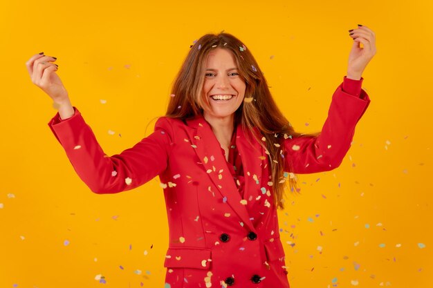 Vrouw plezier in rode jurk op een gele achtergrond gooien met confetti party concept