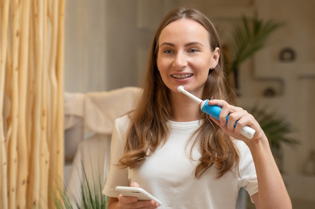Vrouw poetst tanden en leest bericht op telefoon van badkamermeisje met smartphone met behulp van