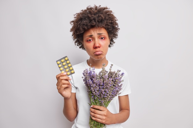 vrouw portemonnees houdt medicijnen en lavendel boeket heeft rode jeukende ogen en neus geïsoleerd over wit