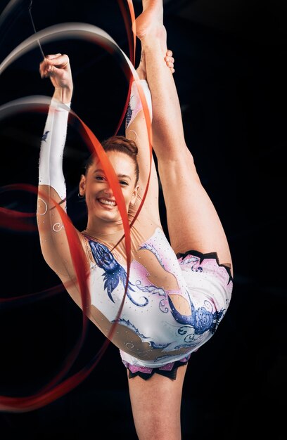 Vrouw portret en blij voor lint gymnastiek sportprestaties of competitie op zwarte achtergrond Flexibele atleet danser en glimlach voor behendige showcase talent en ritmische wedstrijd in studio