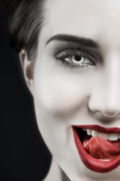 Vrouw portret en gotische lippen in studio voor schoonheid cosmetica en donkere esthetiek met glimlach en edgy Gezicht van model in schurk karakter fantasy contactlens en rode lippenstift op een zwarte achtergrond