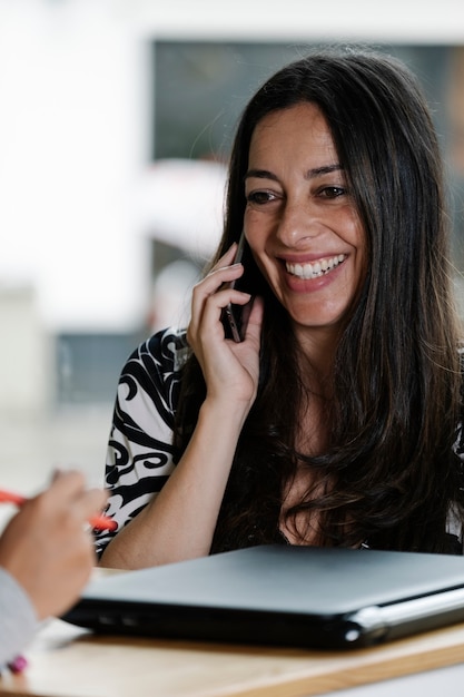 Vrouw praat met haar mobiele telefoon met een lachend gezicht