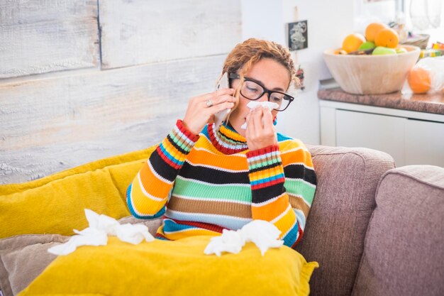 Foto vrouw praat op de mobiele telefoon terwijl ze thuis aan verkoudheid en griep lijdt