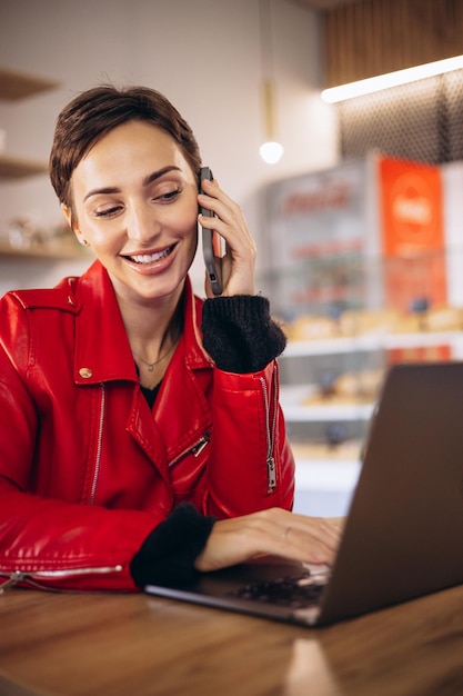 Vrouw praten aan de telefoon en studeren op laptop in een café