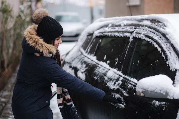 Vrouw probeert auto bij vorst te openen. De deur is bevroren. Winter