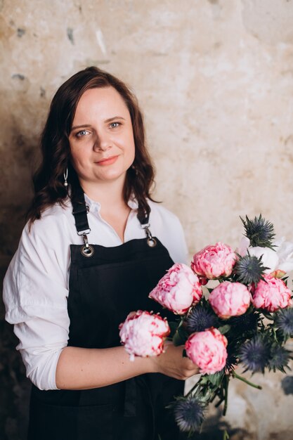 Vrouw professionele bloemist in haar atelier met bloemen in handen