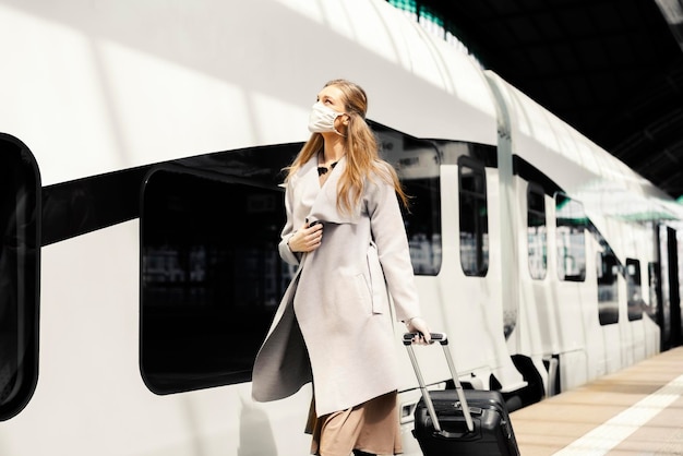 Vrouw reist per trein tijdens pandemie met gezichtsmasker