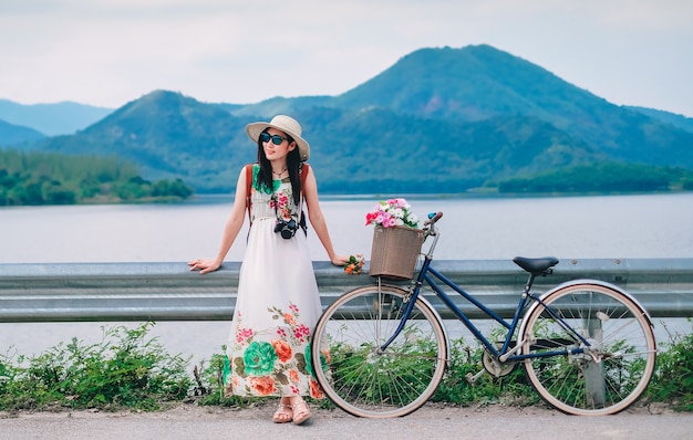 vrouw reiziger en een fiets naast de weg in de buurt van het meer achtergrond is de berg.