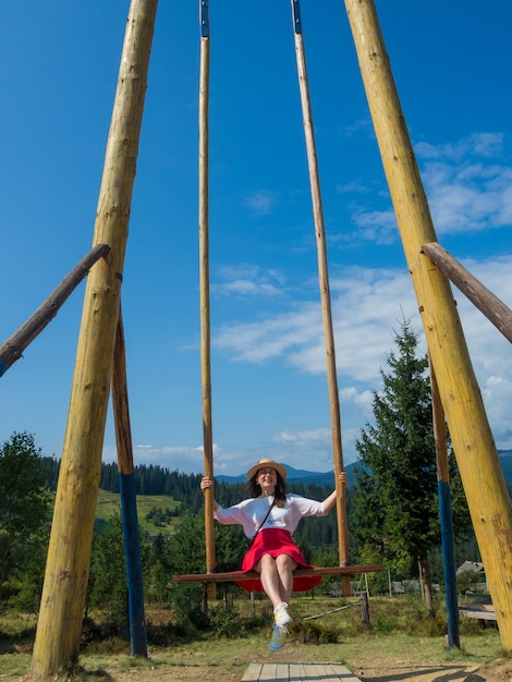 Vrouw reiziger genieten van swingen op hemelse schommel en uitzicht op de bergen